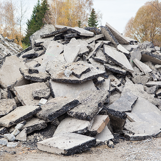 Ein großer Haufen zerbrochener Betonplatten und Schutt im Freien, mit Bäumen im Hintergrund.