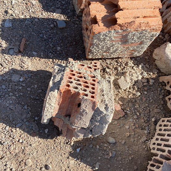 Zerbrochene Ziegel liegen verstreut im Sonnenlicht auf dem Boden.