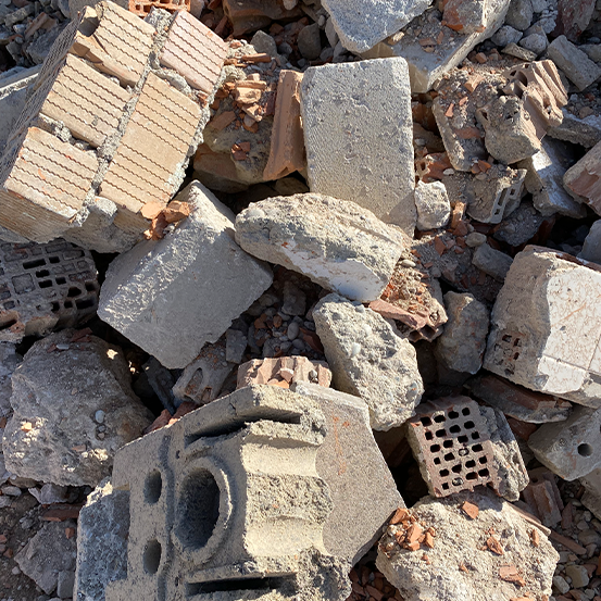 Haufen aus grauem und braunem Beton und Lehmziegeln, einige davon zerbrochen, mit verstreuten kleinen Steinen.