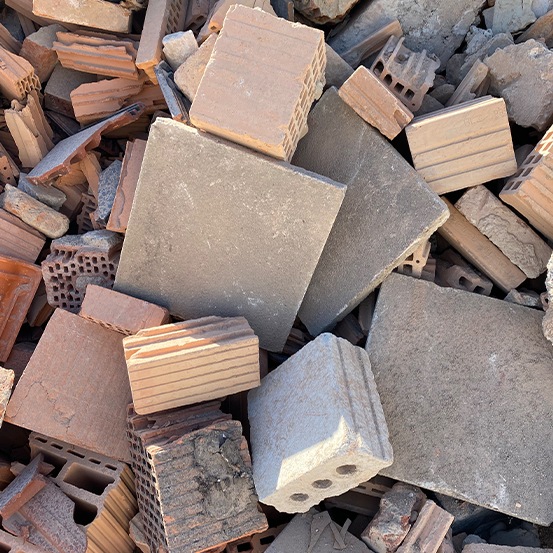 Ein Stapel Ziegel und Fliesen unterschiedlicher Größe in Rot- und Grautönen, ungleichmäßig verstreut.