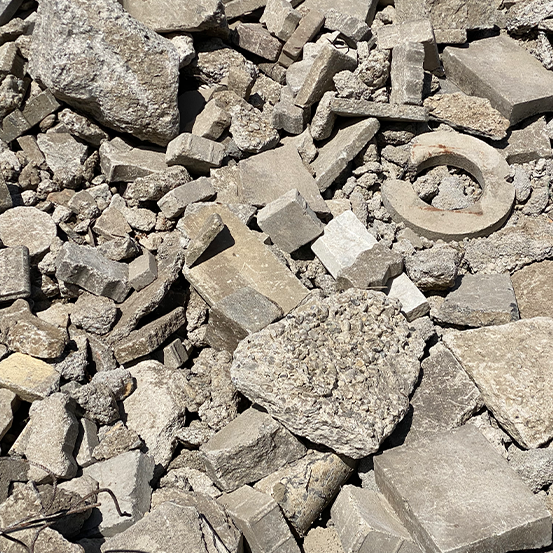 Ein Haufen zerbrochener Betonplatten und Schutt auf dem Boden im Sonnenlicht.