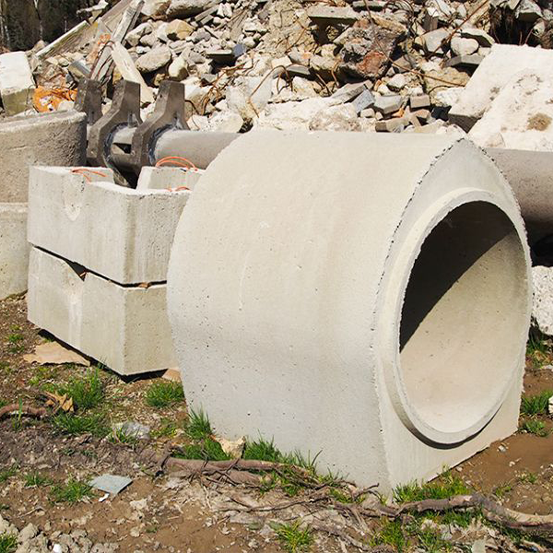 Betonrohre und -blöcke auf einer Baustelle, im Hintergrund Schutt.