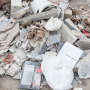 Ein Trümmerhaufen mit Betonsplittern, Papier und verschiedenen verstreuten Gegenständen.