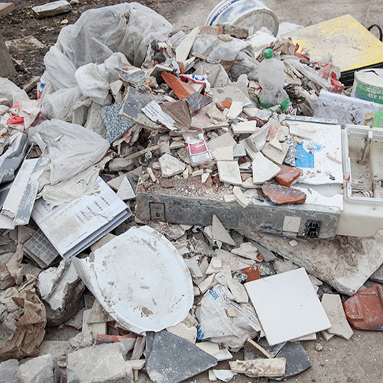 Ein Haufen Bauschutt, darunter Fliesen, Plastiktüten, Flaschen und kaputte Materialien, verstreut auf dem Boden.