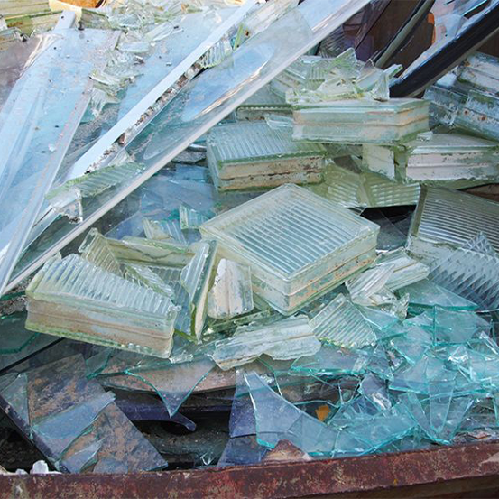 Auf dem Boden verstreute Glassplitter, darunter zerbrochene Scheiben und große Fragmente, die das Licht reflektieren.