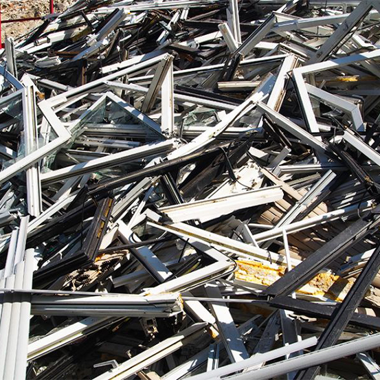 Ein großer Haufen weggeworfener Metallfensterrahmen, die wahllos im Freien gestapelt sind.