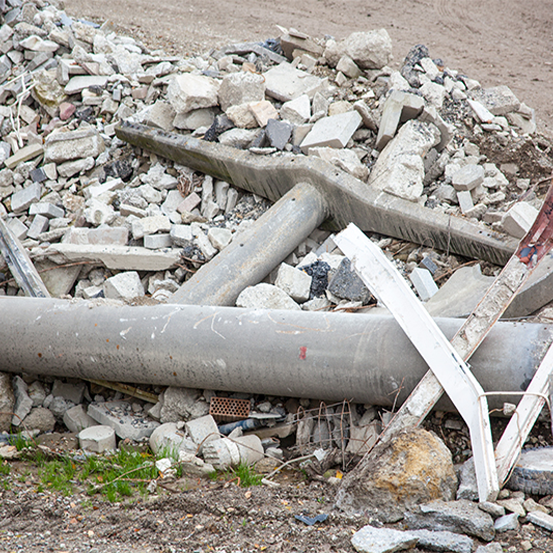 Haufen aus Betonschutt und kaputten Rohren auf einer Baustelle.