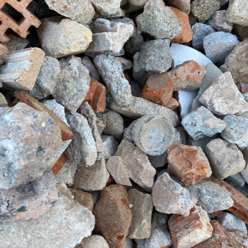 Ein Haufen aus gemischtem Schutt und Trümmern, darunter Ziegelstücke und Betonbrocken, in verschiedenen Grau- und Rottönen.